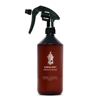 A large sized brown spray bottle labeled Zenology Ambiance Trigger Bakhoor Liquidus featuring an unique botanical illustration with a black spray nozzle.