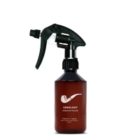 A mid sized brown spray bottle labeled Zenology Ambiance Trigger Tobacco Lignum featuring an unique botanical illustration with a black spray nozzle.