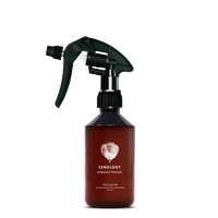A mid sized brown spray bottle labeled Zenology Ambiance Trigger Gossypium featuring an unique botanical illustration with a black spray nozzle.