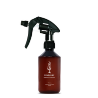 A mid sized brown spray bottle labeled Zenology Ambiance Trigger Titio featuring an unique botanical illustration with a black spray nozzle.