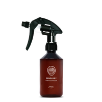 A mid sized brown spray bottle labeled Zenology Ambiance Trigger Ebenus featuring an unique botanical illustration with a black spray nozzle.
