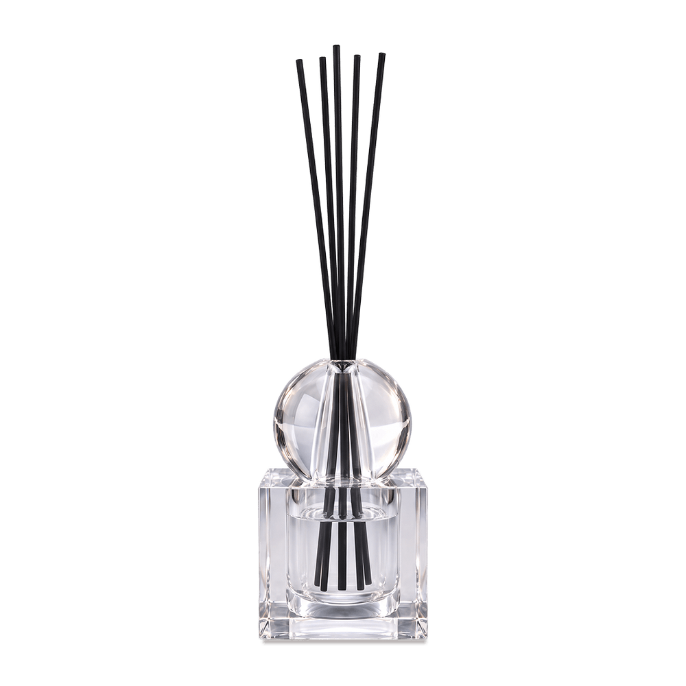 Crystal diffuser with square glass bottle and black reeds gathered in the narrow setting, against a light background.