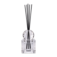 Crystal diffuser with square glass bottle and black reeds gathered in the narrow setting, against a light background.