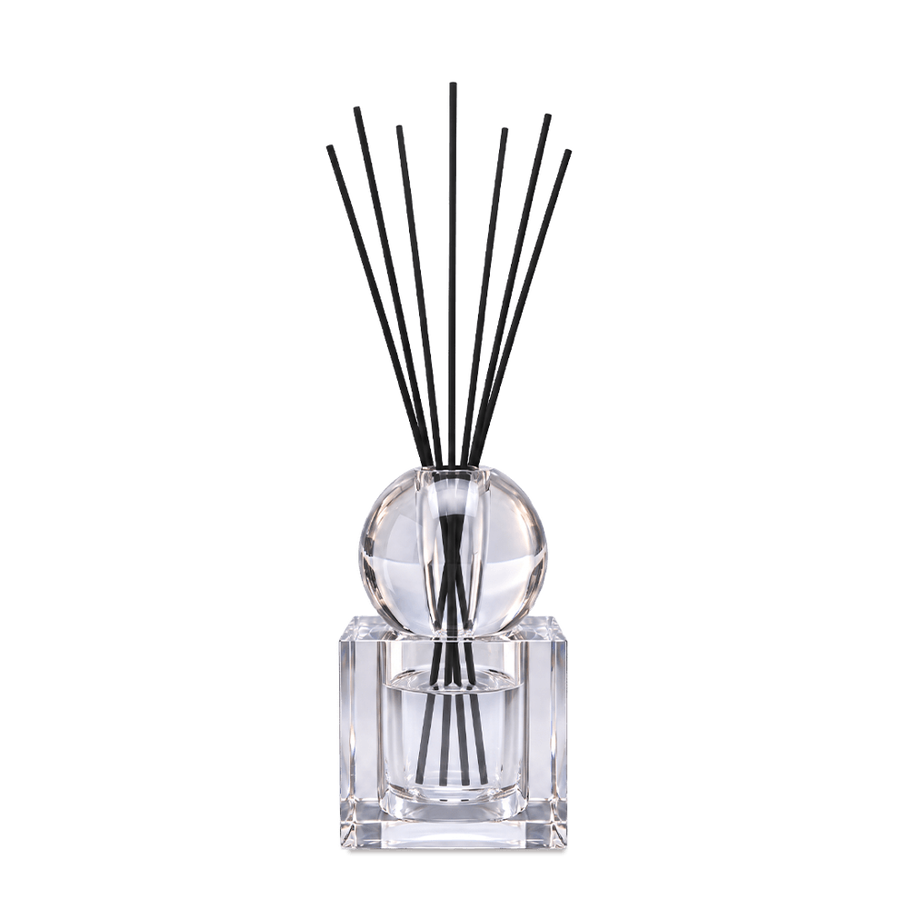 Crystal diffuser with square glass bottle and black reeds in the wide setting, against a light background.