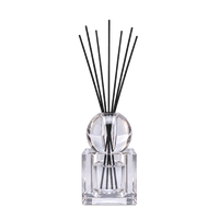 Crystal diffuser with square glass bottle and black reeds in the wide setting, against a light background.